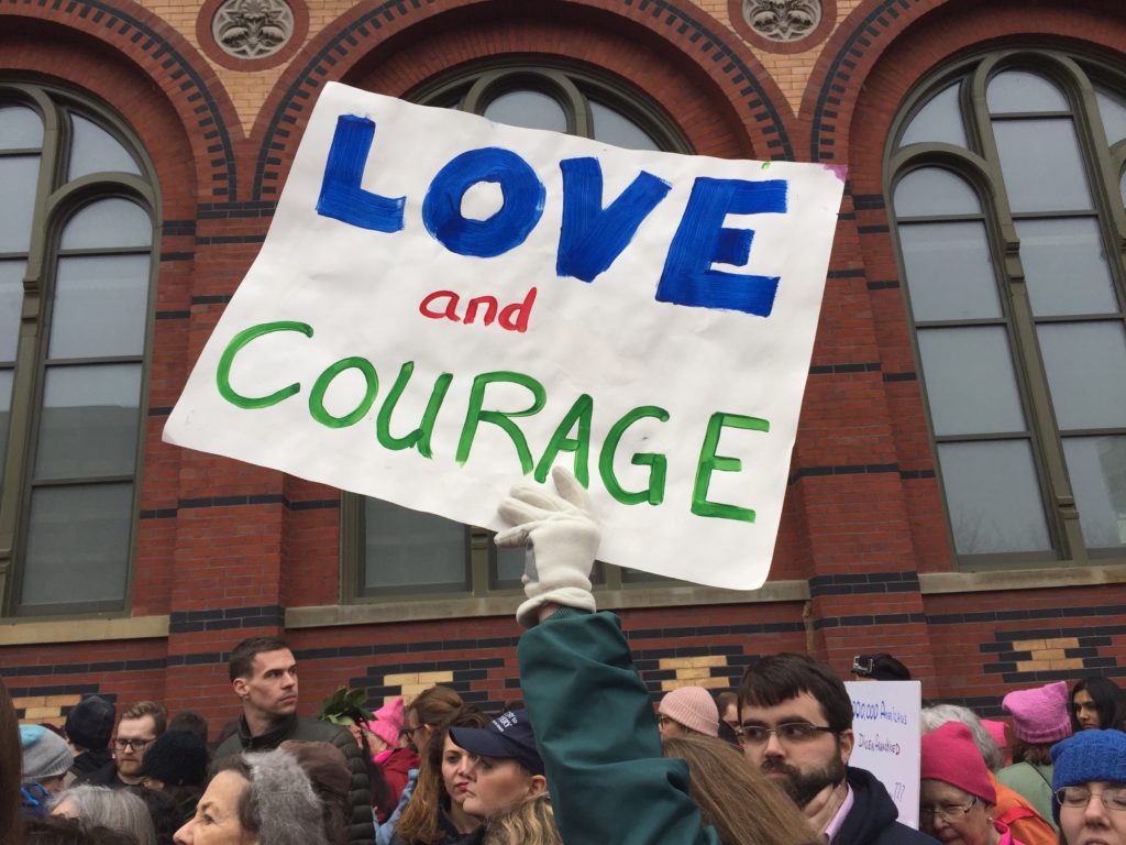 Protester holding a sign with the text Love and Courage
